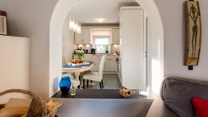 Una cocina moderna con armarios blancos, una mesa de comedor con sillas y un ventanal.