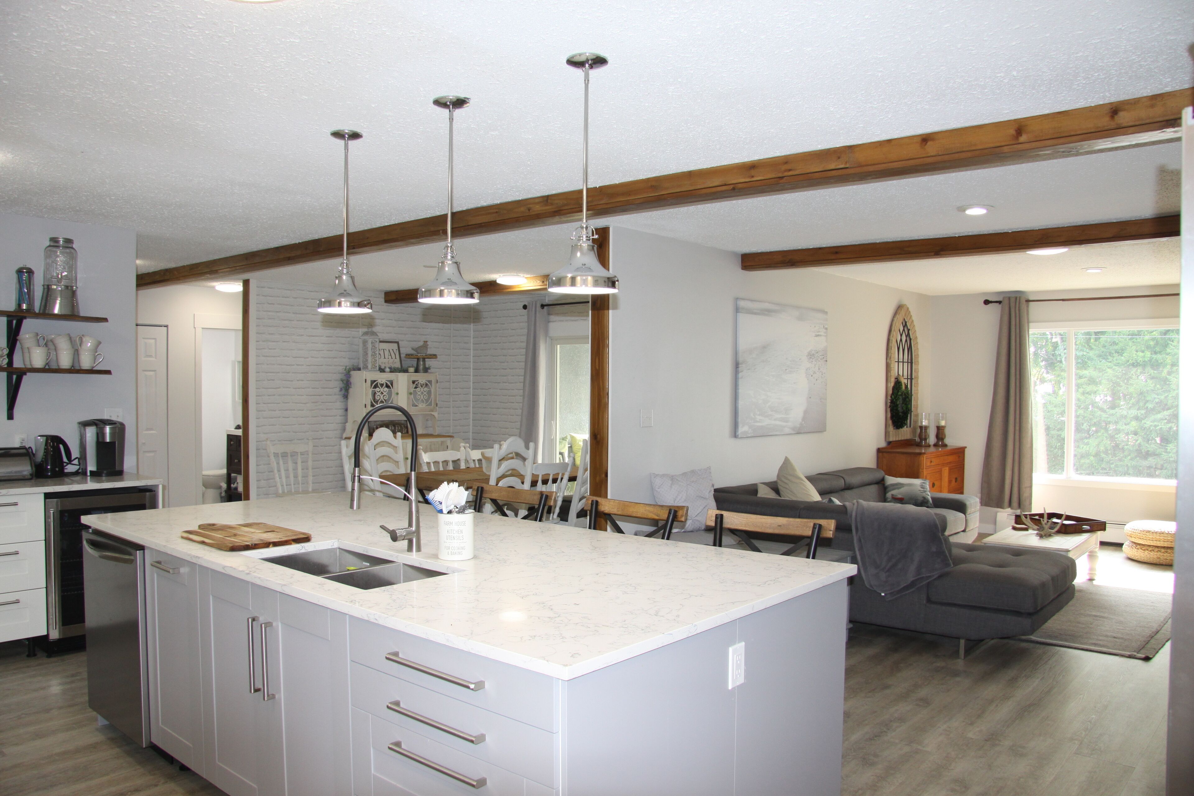 A modern kitchen with a large island, white cabinetry, and pendant lighting.