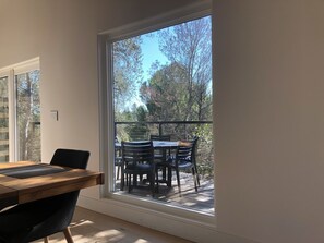 A room with a large window overlooking a wooden deck with outdoor furniture.