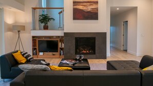A modern living room with a fireplace, a sofa set, a television, and a bookshelf. - Wake Up in Your Own Private Vineyard - Healdsburg (Healdsburg)