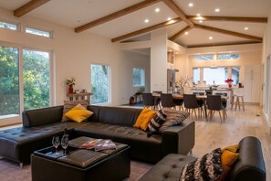 A spacious living area with a modern sofa set, a coffee table with glasses, and a dining area with chairs and a table.
