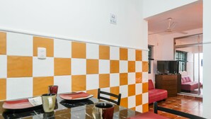 A dining area with a checkered tile wall, a dining table with plates and cups, and a sofa in the background. - FULL APARTMENT NEAR CANCUN AIRPORT (Alfredo V. Bonfil)