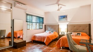 A hotel room with two beds, a ceiling fan, a window with blinds, a mirror, and a small table with a chair. - FULL APARTMENT NEAR CANCUN AIRPORT (Alfredo V. Bonfil)