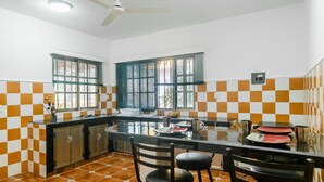 A kitchen with a central island, two windows with blinds, a ceiling fan, and checkered tile walls. - FULL APARTMENT NEAR CANCUN AIRPORT (Alfredo V. Bonfil)