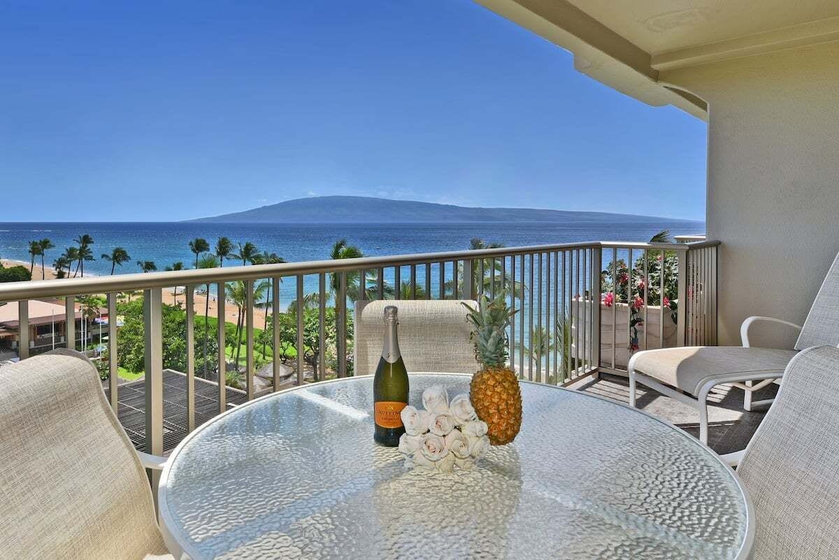 A balcony with a glass table, a bottle, and a pineapple.