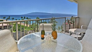 A balcony with a glass table, a bottle, and a pineapple. - BeachFront Luxury 1BR Excellent Views Pool-Whaler 859 (Lahaina)