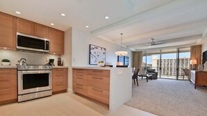 A modern kitchen with built-in appliances and a dining area with a view of the city. - BeachFront Luxury 1BR Excellent Views Pool-Whaler 859 (Lahaina)