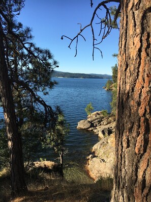 Eine natürliche Landschaft mit Blick auf einen klaren See, einen felsigen Uferstreifen und Bäume.