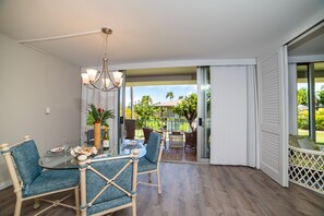 Enjoy meals in this dining area with a glass table and comfortable seating, surrounded by a lush garden view.