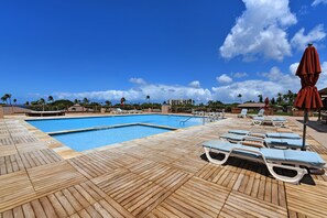Relax by the pool surrounded by lounge chairs and palm trees.