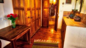 A wooden hallway with a bench, a vase of red flowers, and a rug on the floor. - Casa Encantada (Patzcuaro)
