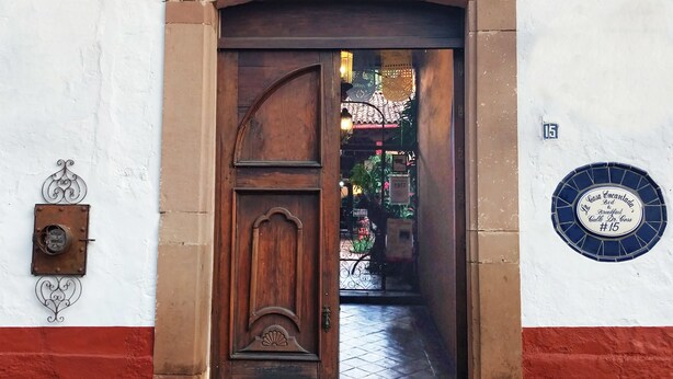 A hotel entrance with a wooden door, a sign above reading "Hotel Casa Encantada," and a number plaque indicating room #15. - Casa Encantada (Patzcuaro)