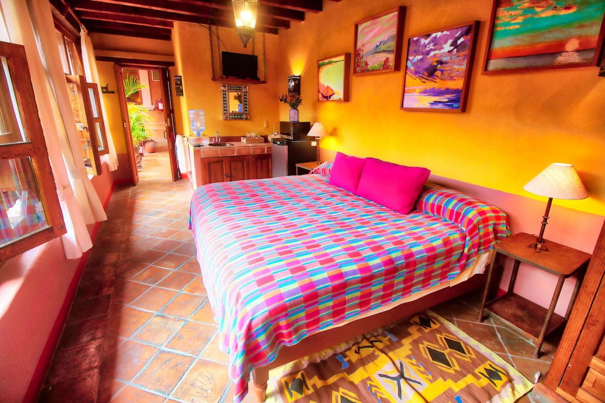 Une chambre d’hôtel avec un grand lit, un bureau, une chaise, une lampe et une fenêtre.
