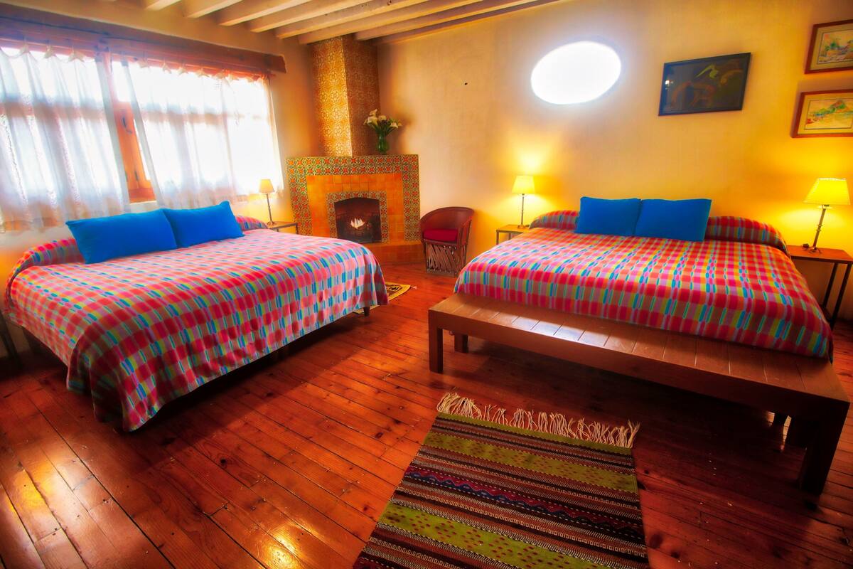 Une chambre avec deux lits, une cheminée et un plancher en bois.