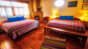 Una habitación con dos camas, una chimenea y piso de madera.