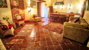 A cozy living room with a tiled floor, a sofa, a chair, and a dining area with a table and chairs. - Casa Encantada (Patzcuaro)
