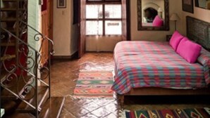 A bedroom with a bed, a window, a mirror, and a staircase. - Casa Encantada (Patzcuaro)