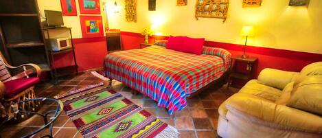 A bedroom with a bed, a sofa, a chair, a desk, and a TV.