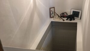 A narrow stairwell with a handrail, a small shelf with decorative items, and a picture frame on the wall. - Coal Miner's Cabin - Near Winterplace, Beckley and Princeton (Shady Spring)