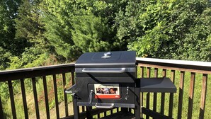 A portable barbecue grill on a wooden deck with a metal railing. - Coal Miner's Cabin - Near Winterplace, Beckley and Princeton (Shady Spring)