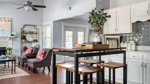 Eine moderne Küche mit weißen Schränken, einer Holztischinsel und einem Deckenventilator.