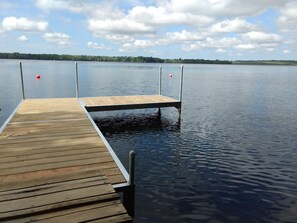 A wooden dock extending into calm water with a clear sky and distant trees. - Quaint cottage on the water (Old Town)