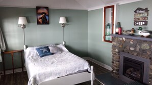 A bedroom with a bed, two bedside lamps, a stone fireplace, and a welcome sign above the fireplace.