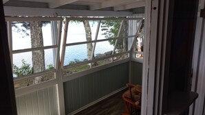 A room with a view of a lake, a rocking chair, and wooden flooring.