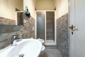 Une salle de bain avec un grand lavabo blanc, des toilettes et une douche à parois de verre.