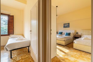 Une chambre avec deux lits, une porte en bois et une vue sur les arbres par la fenêtre.