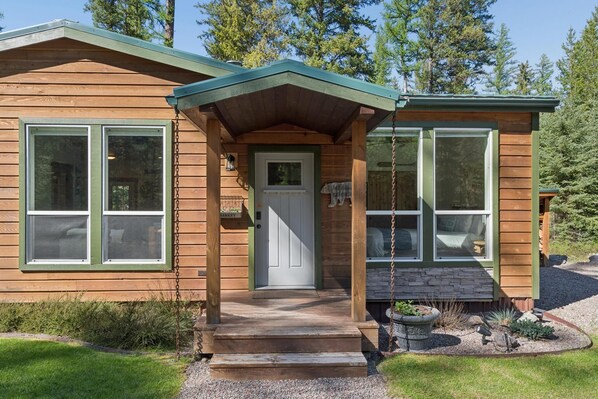 A wooden cabin with a porch, a door, and a window.
