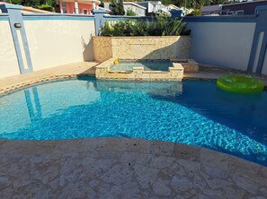 A swimming pool with clear blue water, a small hot tub, and a green inflatable ring. - Family Escape Resort, piscina privada cerca de la playa (Luquillo)