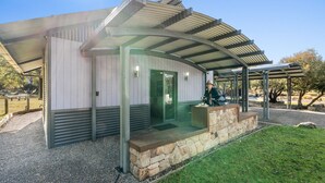 Ein modernes Gebäude mit überdachter Terrasse, Steinstufen und einer Glastür.