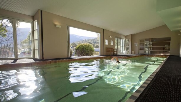 Ein Hallenbad mit klarem Wasser, großen Fenstern und Bergblick.