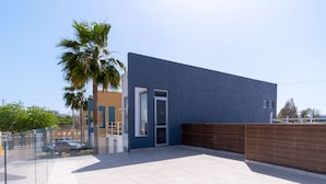 A modern building with a blue exterior, a glass door entrance, and a tiled patio area.