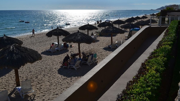 A beach with sun loungers, thatched umbrellas, and a clear view of the sea.