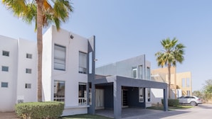 A modern building with a flat roof, large windows, and a covered entrance.