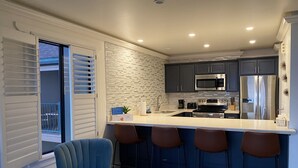 Uma cozinha moderna com uma ilha grande, banquetas e vista para o exterior.