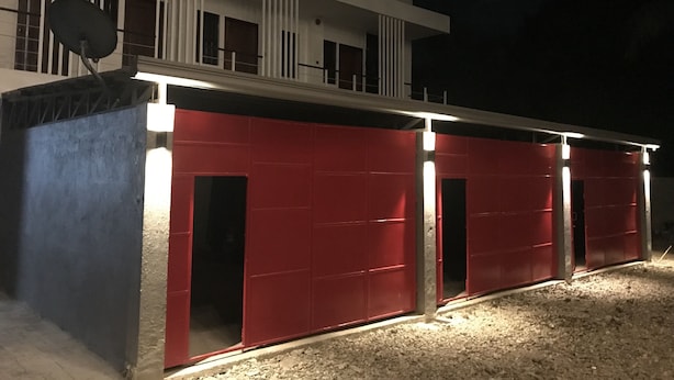 A modern building with a red facade and multiple garage doors. - Mayumi Lodge, Perfect for couples. Cozy and Nice! Fast Internet (Puerto Princesa)
