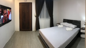 A hotel room with a bed, a TV, a door, and a window with curtains. - Mayumi Lodge, Perfect for couples. Cozy and Nice! Fast Internet (Puerto Princesa)