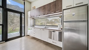 A modern kitchen with stainless steel appliances, a large window, and a view of the outdoors. - Ecocrackenback 2 'Sustainable chalet close to the slopes.' (Crackenback)