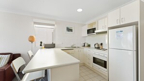 Una cocina moderna con armarios blancos, horno empotrado, microondas y refrigerador.