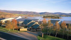 Un hotel a orillas del lago con varias edificaciones, un estacionamiento y vistas al lago y a las montañas.