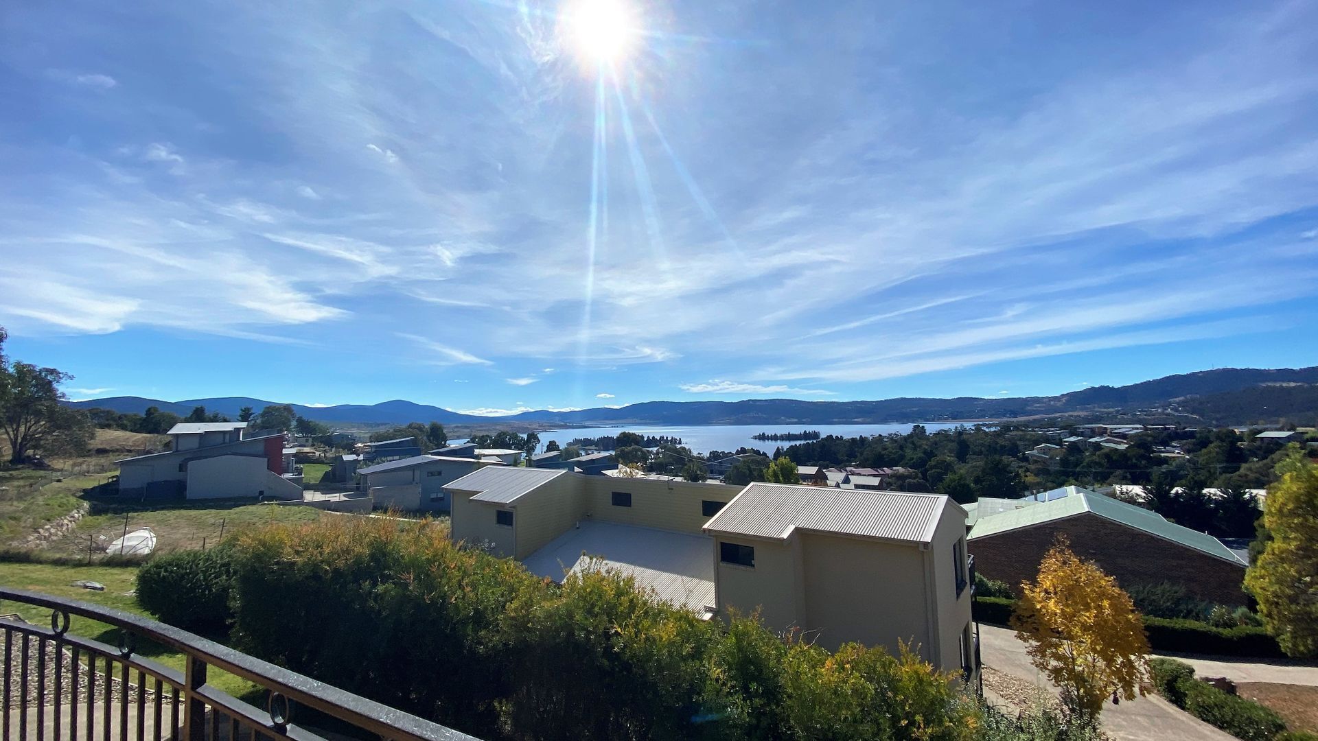 A residential area with houses, a clear sky, and a lake in the distance.