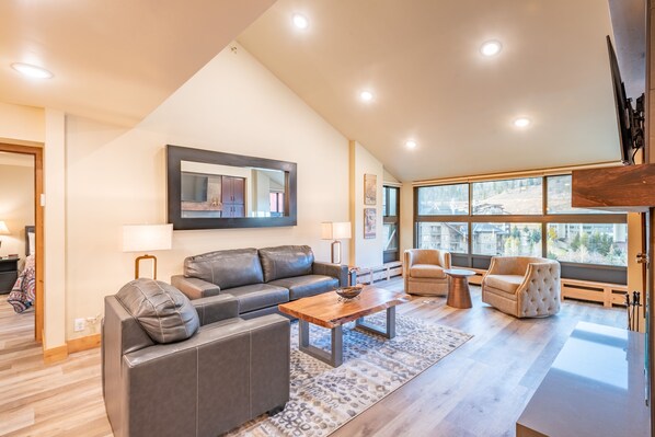 A modern living room with a gray sofa, a wooden coffee table, and a beige armchair.