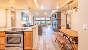 Una cocina amplia con una isla grande, armarios de madera y un comedor con mesa y bancos de madera.