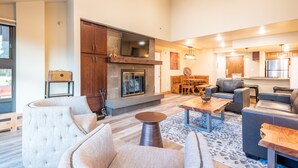 Un amplio salón con chimenea, muebles modernos y una cocina al fondo.