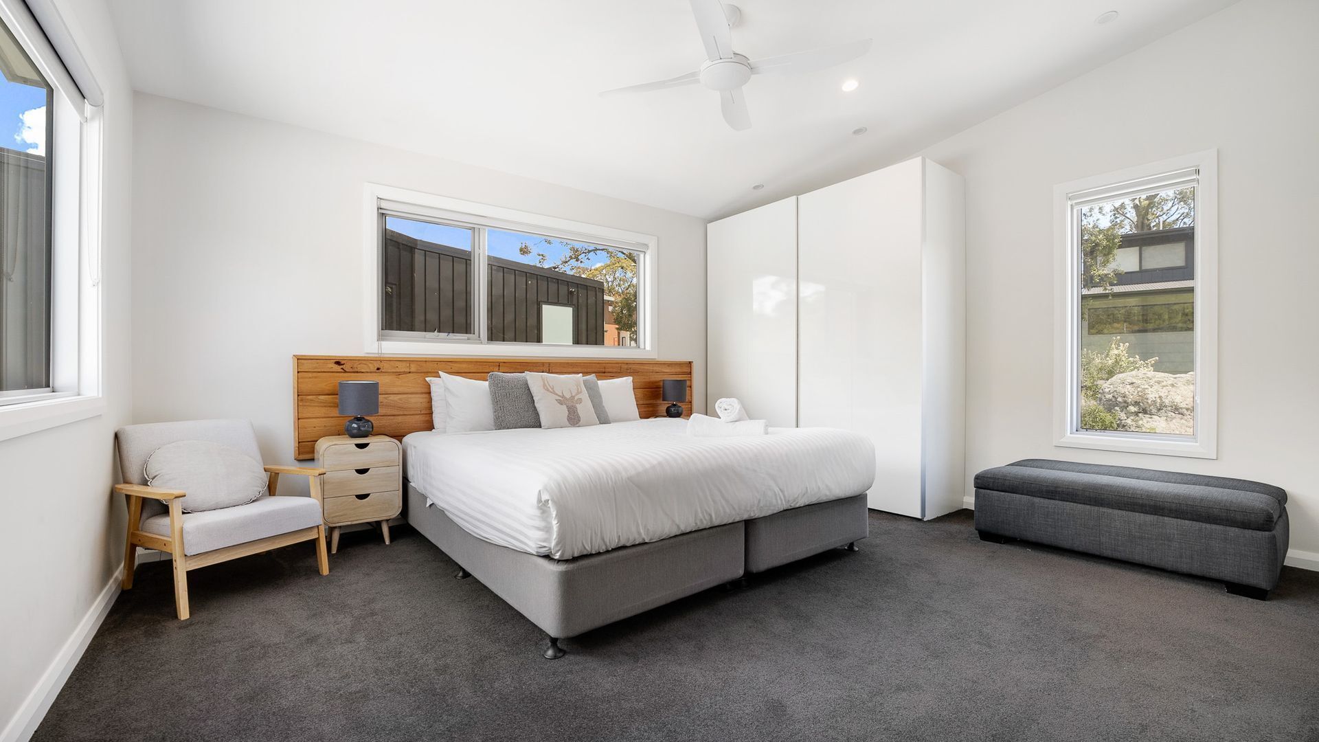 A modern bedroom with a large bed, bedside tables, a chair, and a bench.