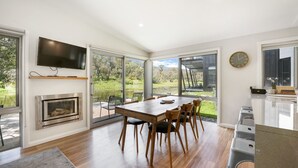 A modern kitchen with a large dining table, built-in oven, and a TV mounted on the wall.