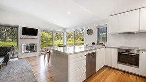 A modern kitchen with a large island, built-in appliances, and a view of a garden through large windows.